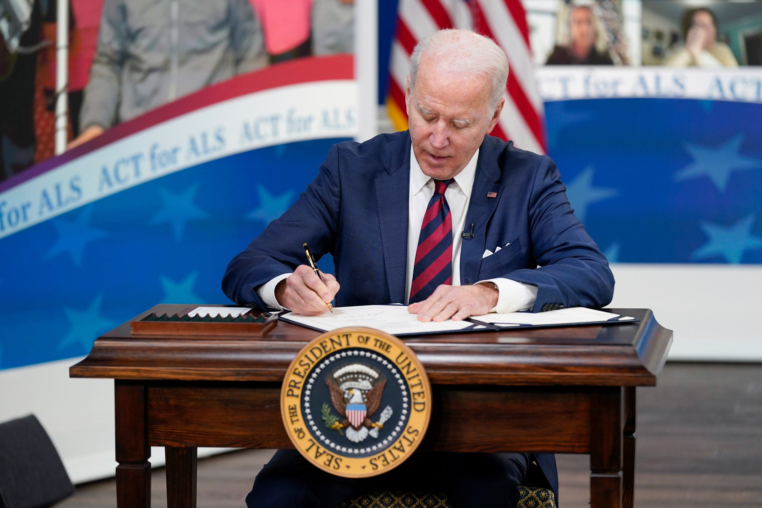 President Biden at a desk signing a document.