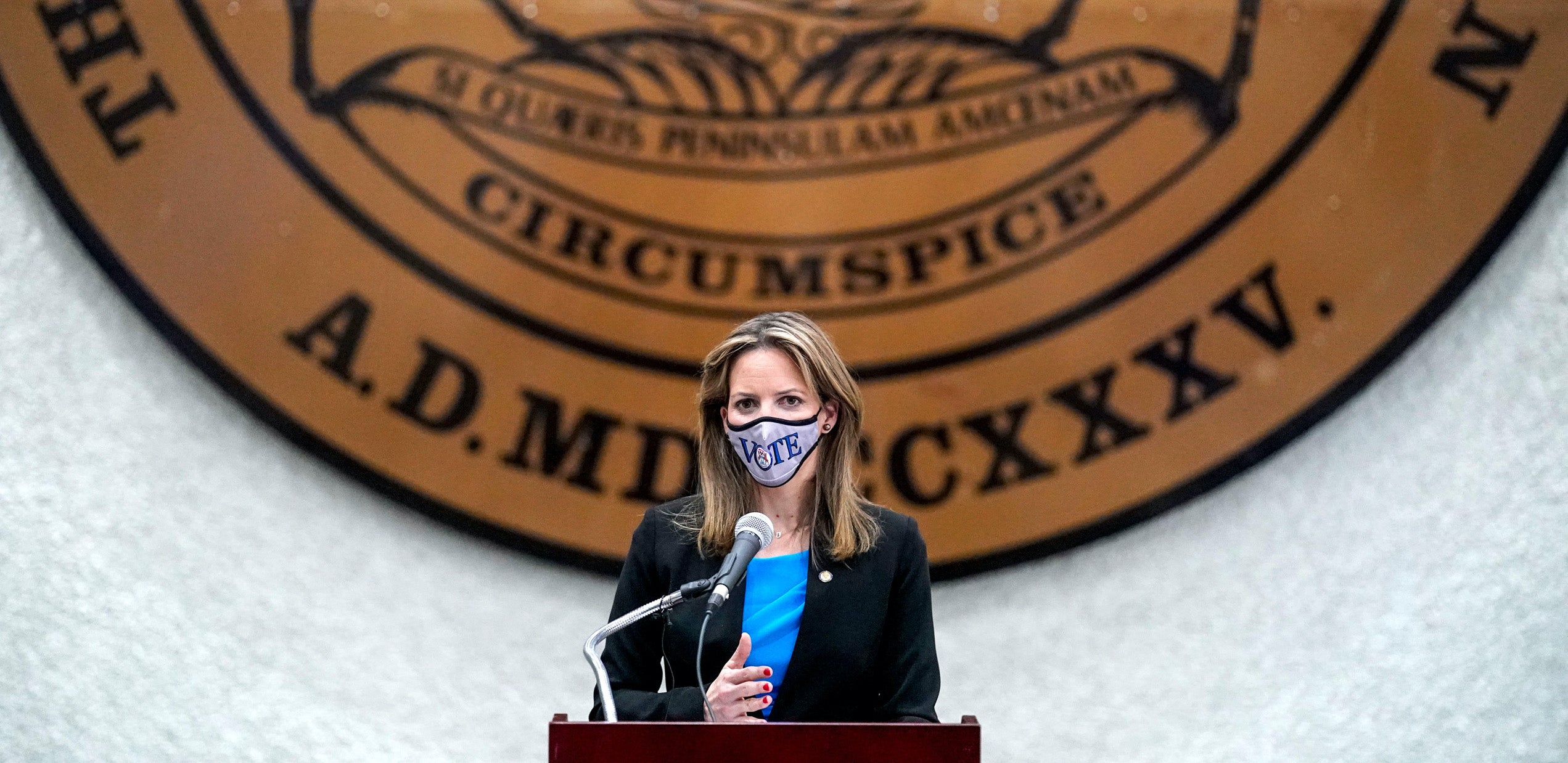 Woman speaking with mask into microphone