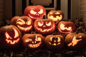 Several illuminated jack-o-lanterns in front of a house.