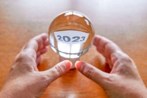 Two hands holding a clear glass ball with the year 2023 inside.